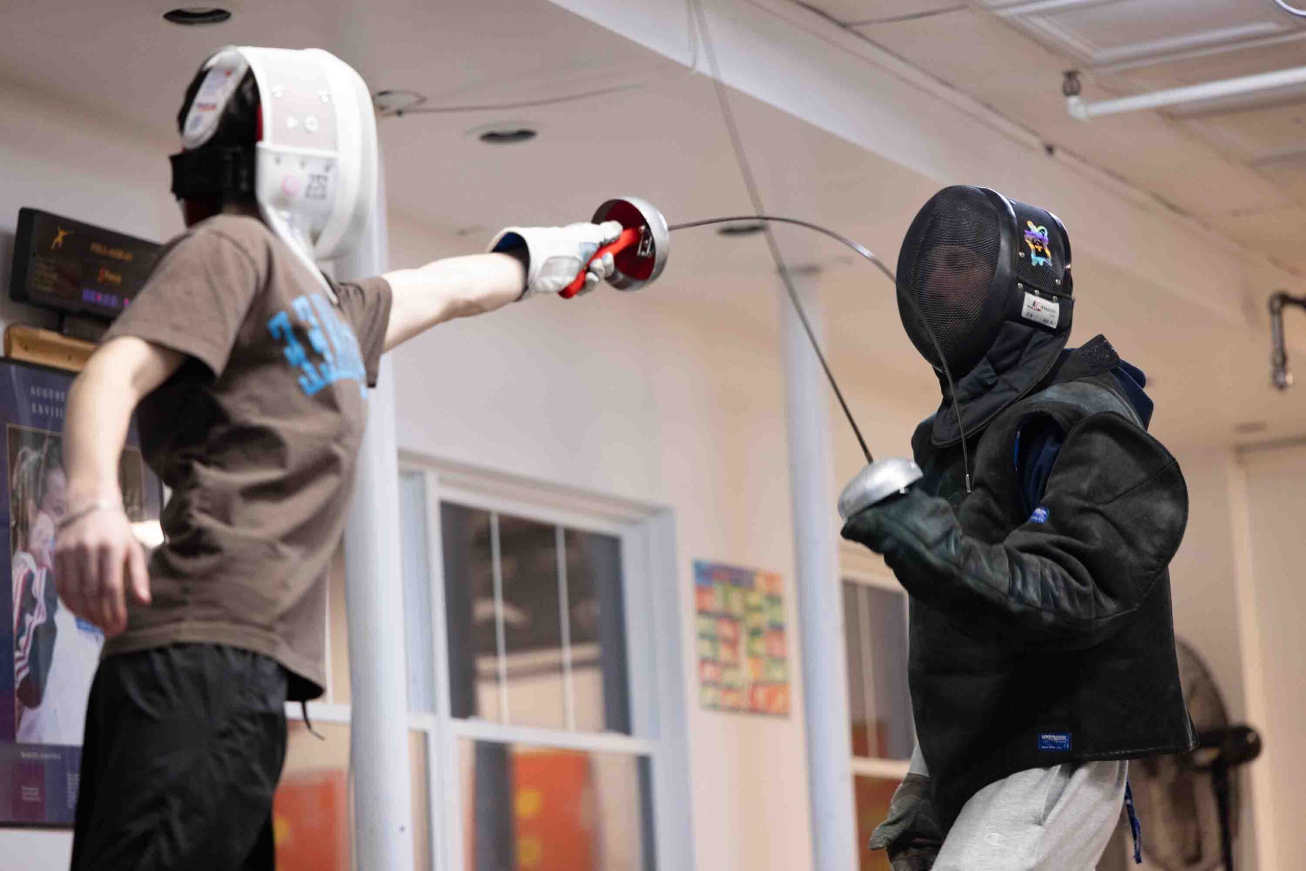 Two fencers practice defending.