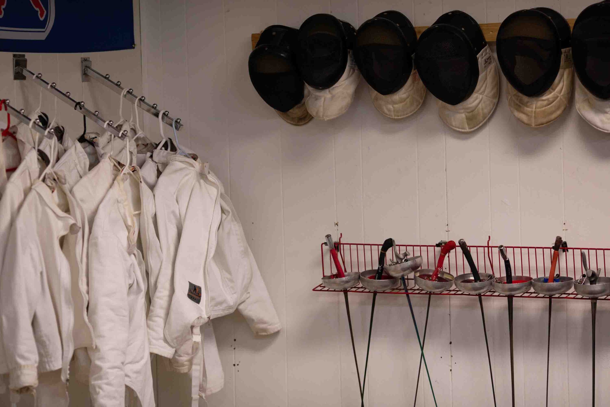 Fencing gear for students hang in the corner of the club.