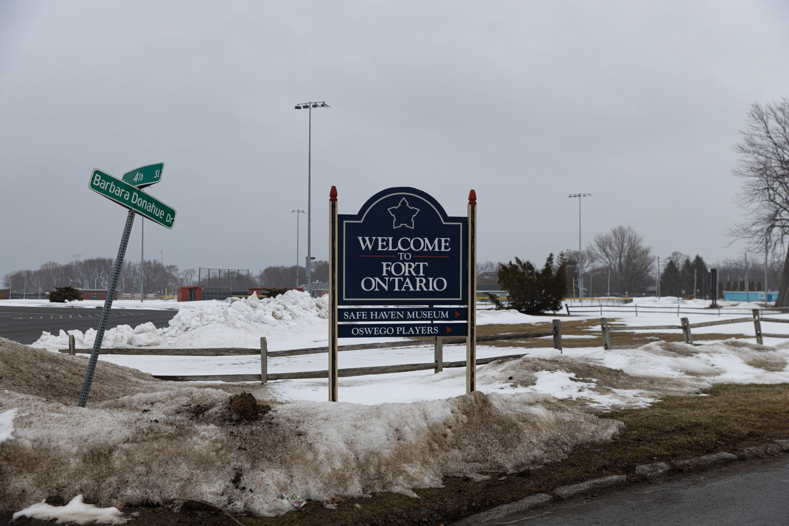 In the snow, the "Welcome to Fort Ontario" sign also includes an arrow leading to the Safe Haven museum.