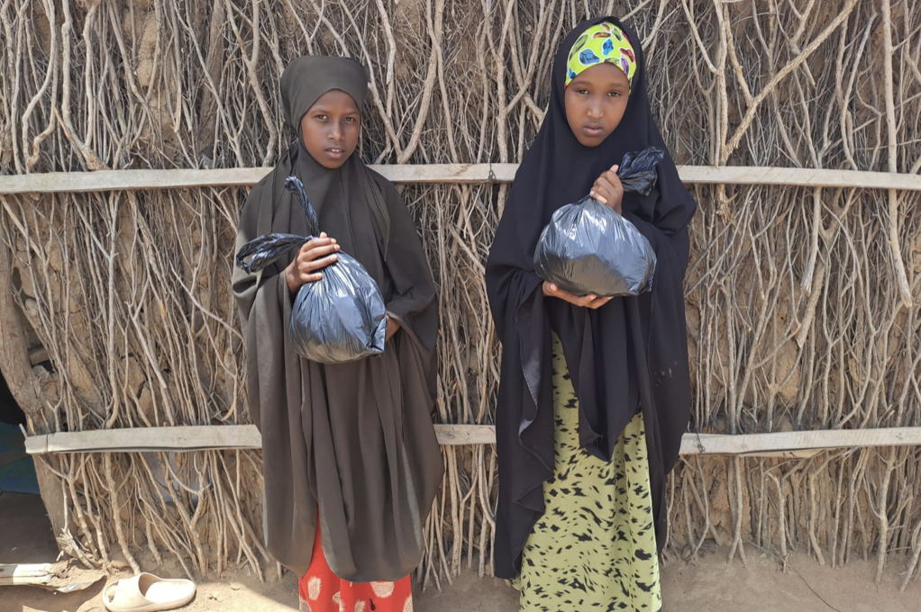 Children at Dadaab’s Ifo 2 refugee camp in Kenya hold a black bag filled with clothing donated by Sadaqa Foundation Inc.