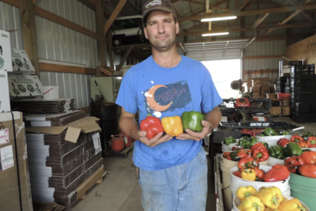 Ryan Pekarek holds three bell peppers he grew on his farm in Dwight, Nebraska.