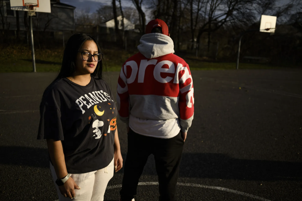 Rafael’s sister, Miranda, stands next to Rafael on a basketball court. She is facing the camera but he is turning his back.