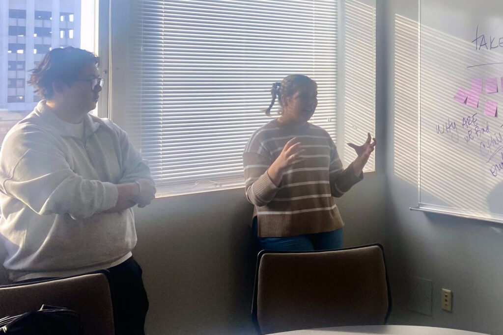 Two people stand in front of a window