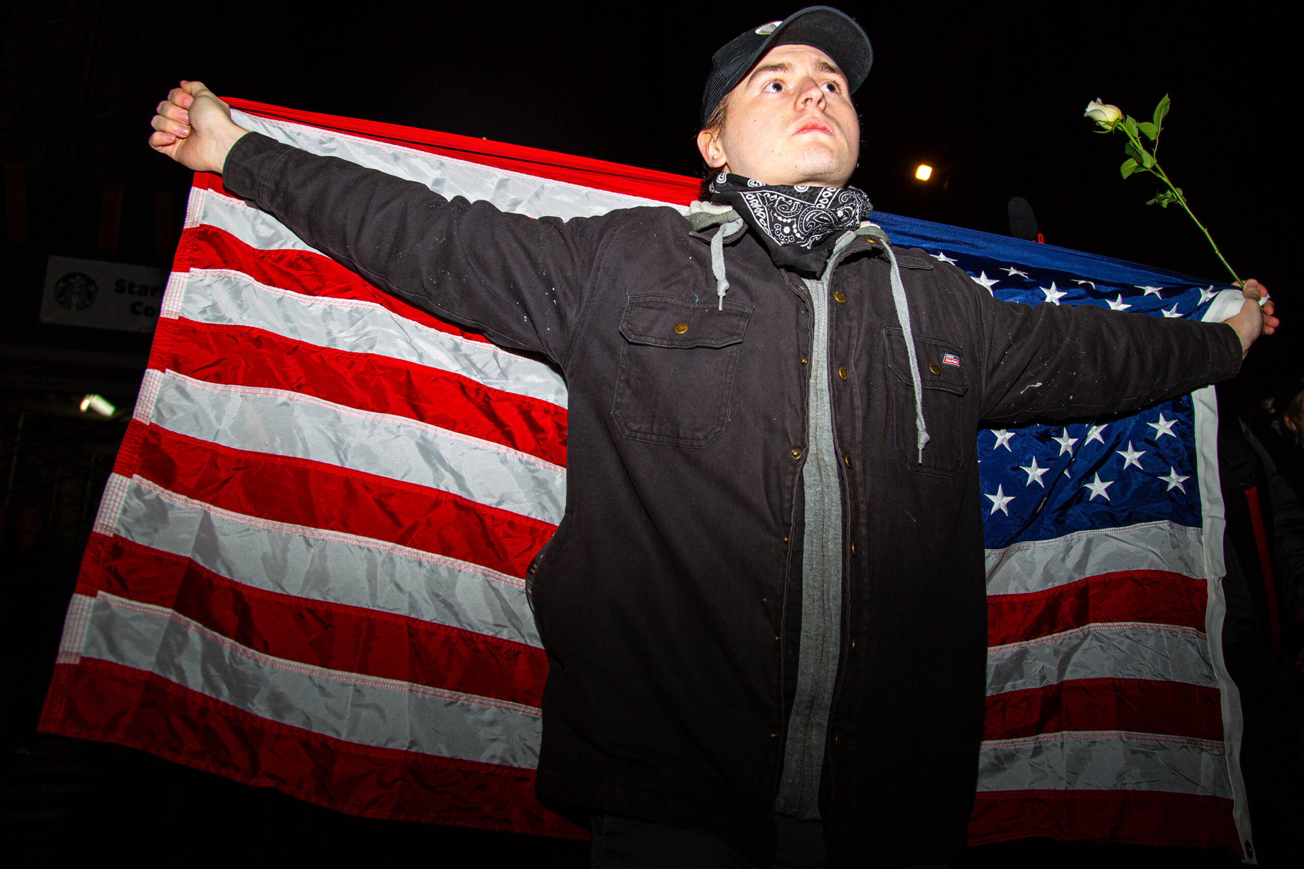 A man holds out a U.S. flag during a gathering in New York City on January 7, 2026, following the killing of Renee Good in Minneapolis.