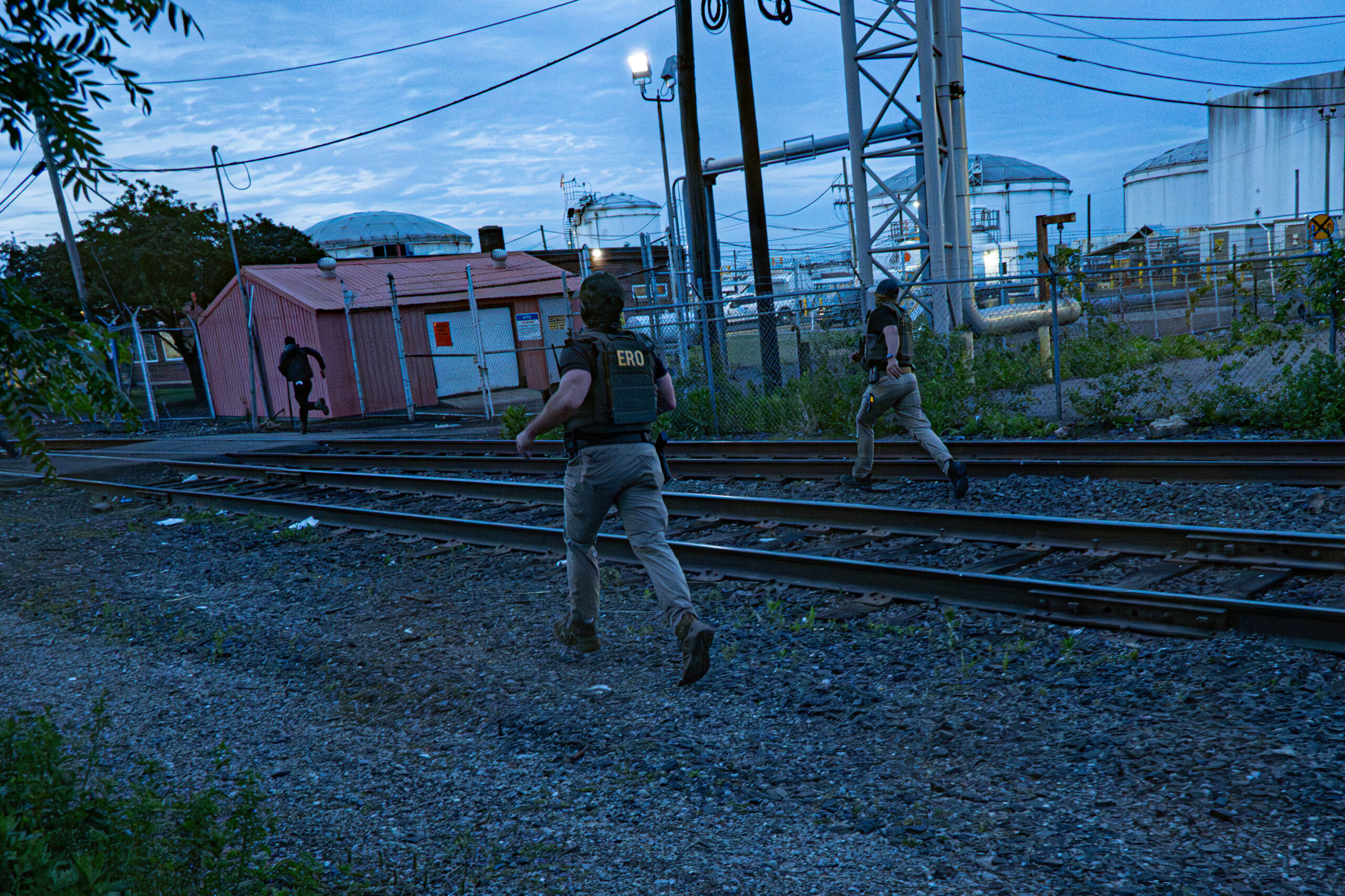 Enforcement and Removal Operations agents pursue a protester along railroad tracks following a confrontation outside Delaney Hall detention center in Newark, N.J., on May 26, 2026.
