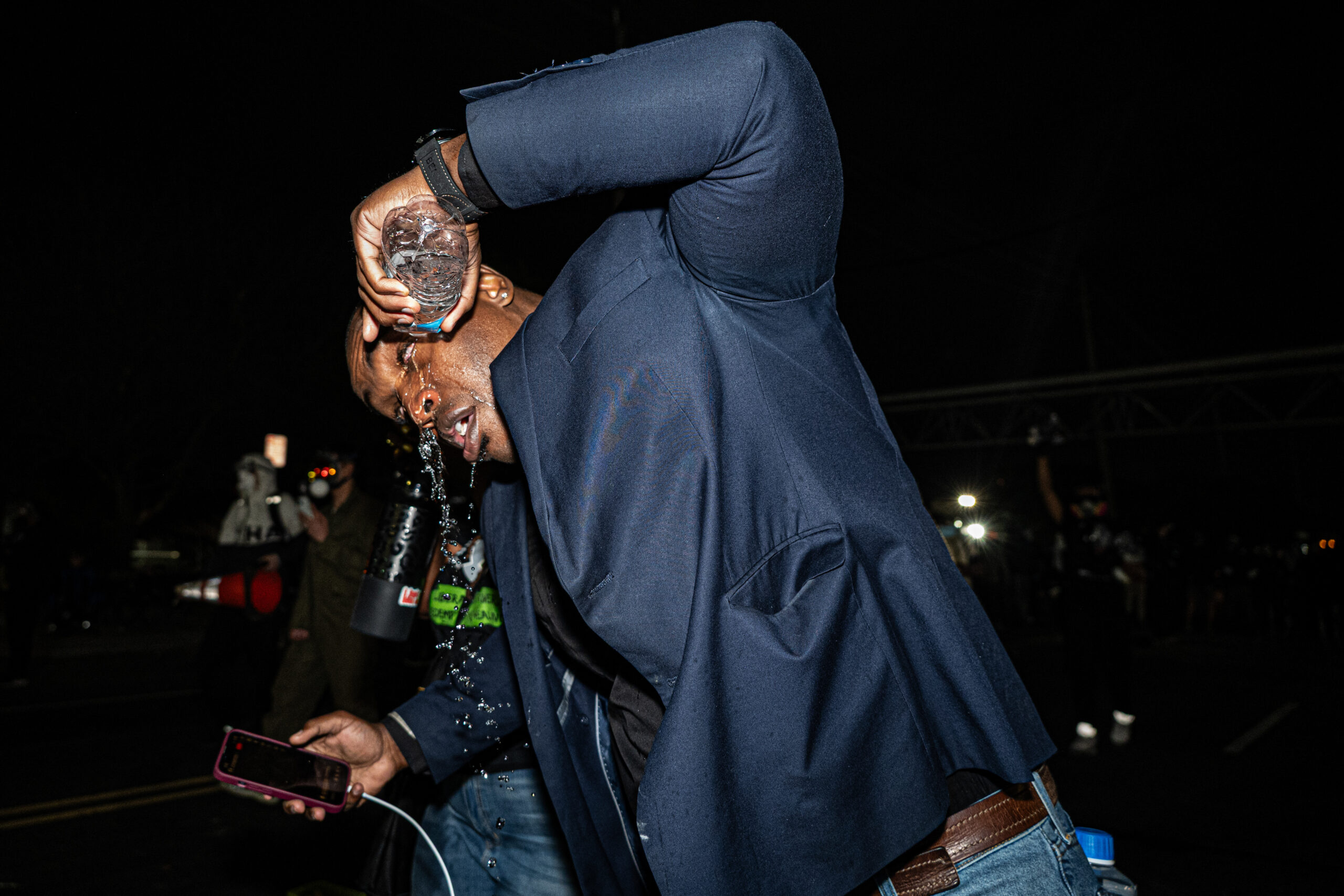 Minister Archange Antoine rinses their eyes after being struck by pepper spray during a police riot outside Delaney Hall detention center in Newark, N.J., on May 29, 2026.