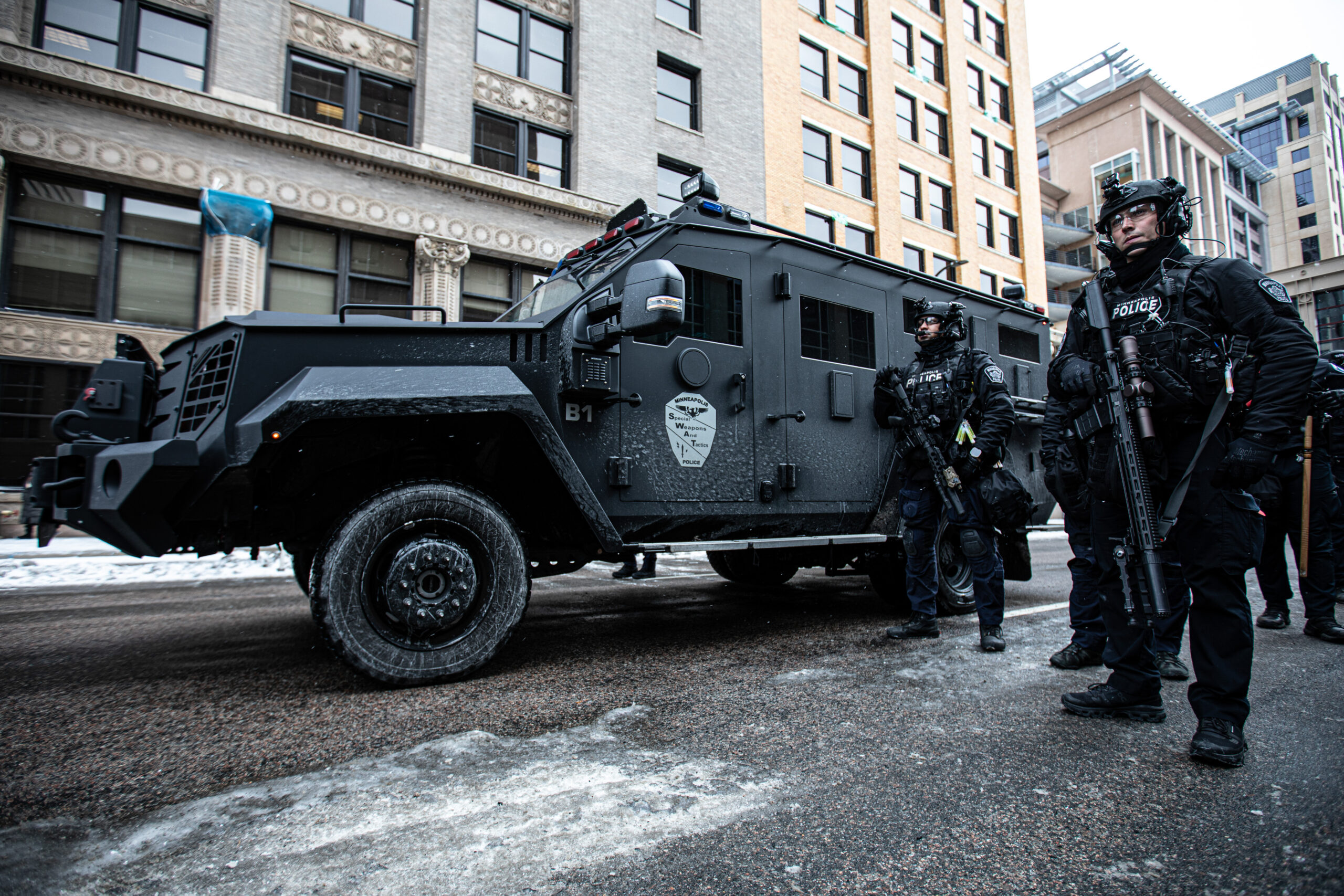Minneapolis police officers stand by with a Lenco Bearcat armored vehicle near a protest against far-right activist Jake Lang in Minneapolis on Jan. 17, 2026. Officers asked demonstrators to stay off the roads about an hour after the protest began. Police maintained a largely neutral presence despite several physical altercations during Lang's appearance.